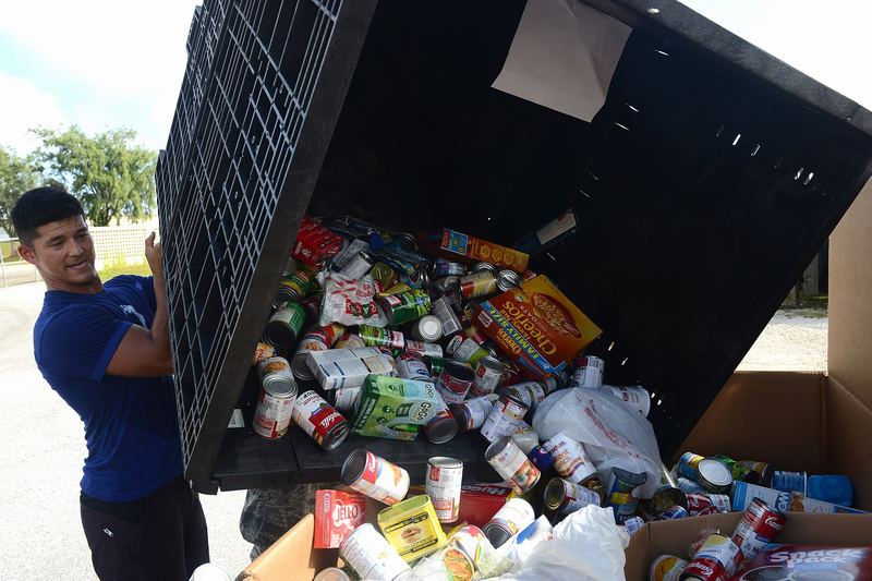 Staff Sgt. Donald Derusha, 36th Munitions Squadron bay chief, empties canned goods into a box for Operation Christmas Drop Dec. 4, 2015, at Andersen Air Force B